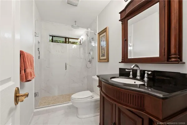 a bathroom with a sink a toilet a mirror and shower
