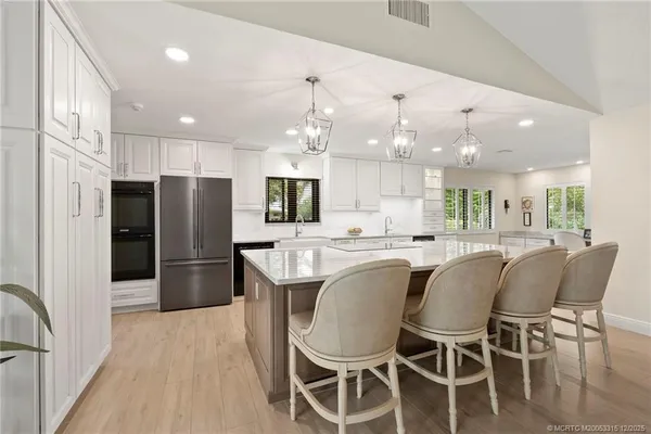 a kitchen with stainless steel appliances kitchen island granite countertop a refrigerator a stove a sink dishwasher with a dining table and chairs