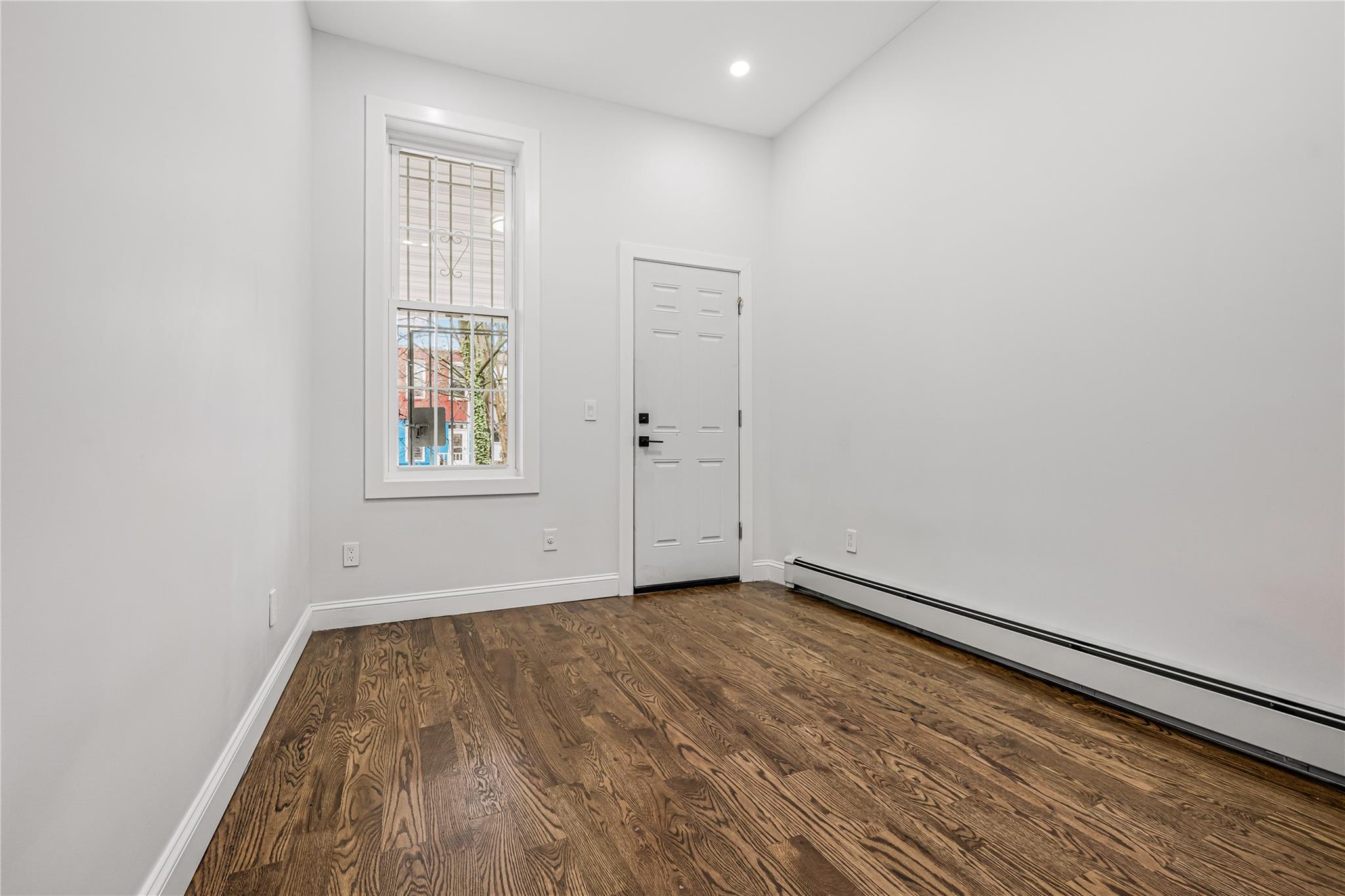 164 Atkins Avenue, Unit 1 Brooklyn, NY 11208 - Photo 2 of 18 an empty room with wooden floor and windows