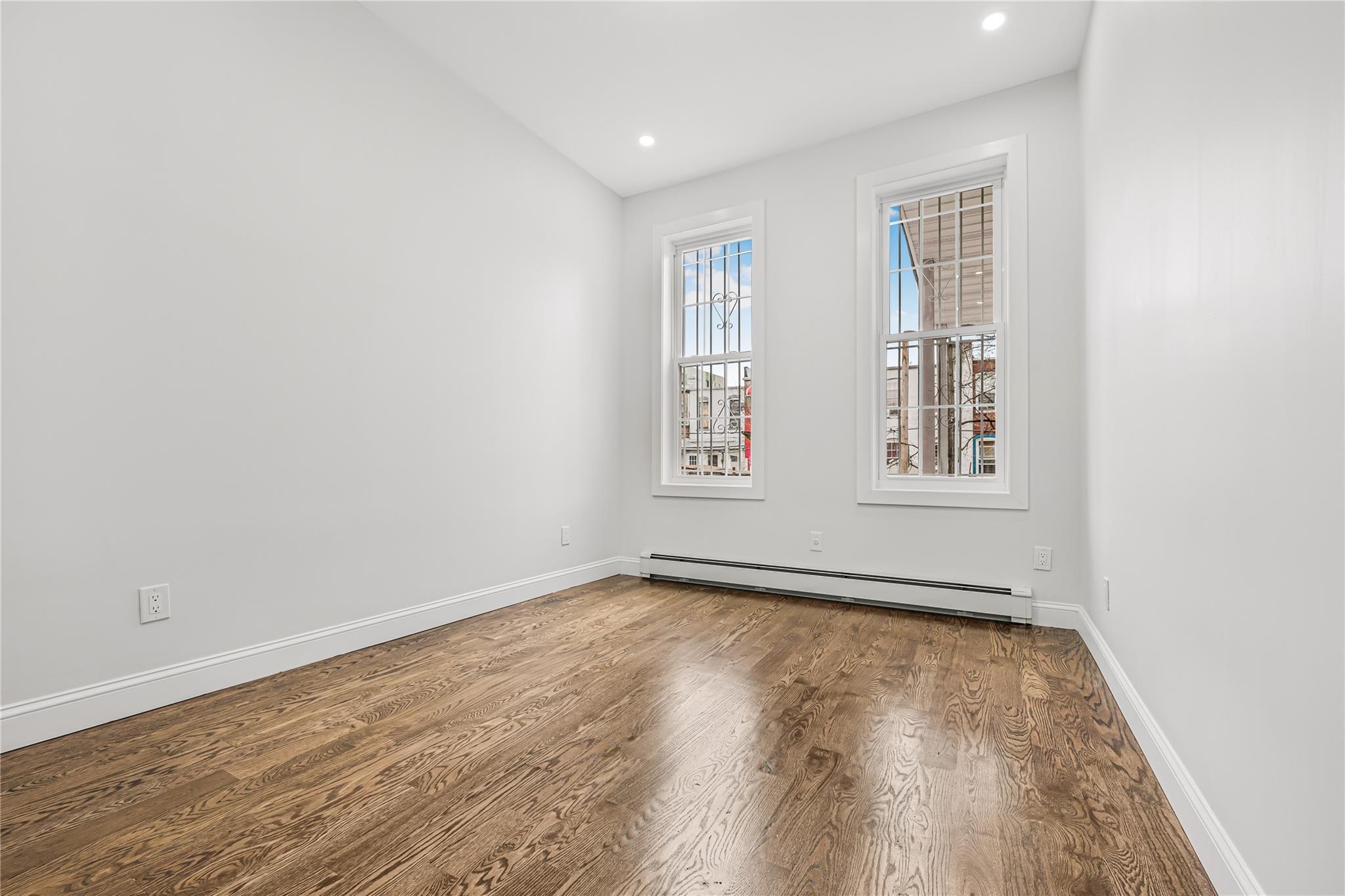 164 Atkins Avenue, Unit 1 Brooklyn, NY 11208 - Photo 4 of 18 an empty room with wooden floor and windows