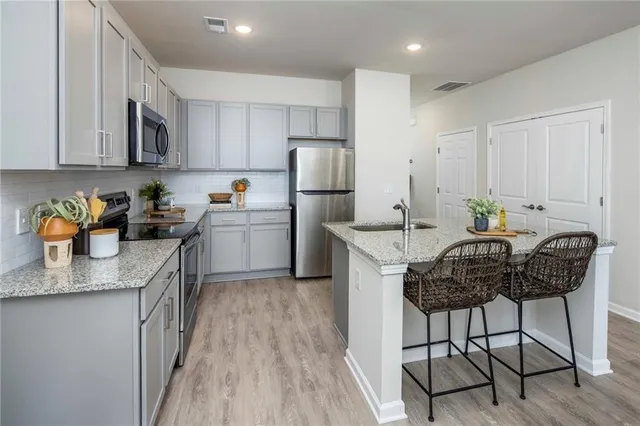 a kitchen with stainless steel appliances granite countertop a table chairs sink and cabinets