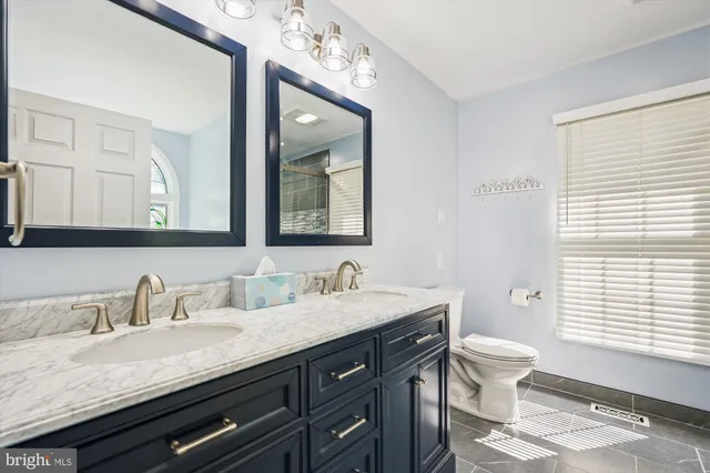a bathroom with a granite countertop double vanity sink a mirror and a window