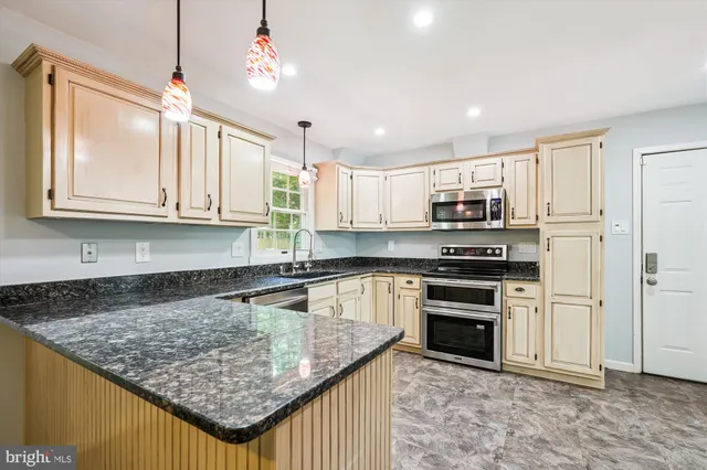 a kitchen with kitchen island granite countertop a stove sink and cabinets