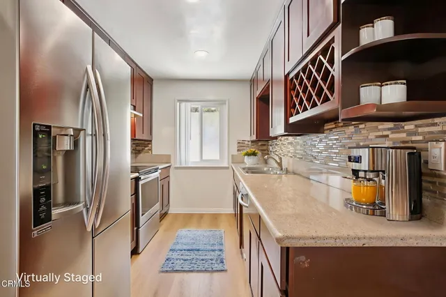 a kitchen with stainless steel appliances granite countertop a sink and a refrigerator