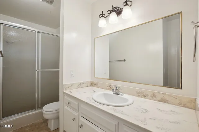 a bathroom with a granite countertop sink toilet and shower