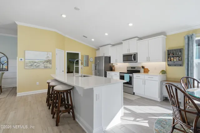 a living room with stainless steel appliances furniture a dining table and kitchen view