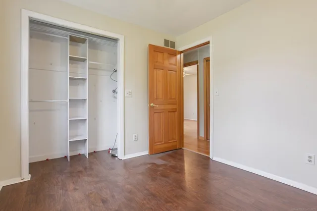a view of an empty room with closet and wooden floor