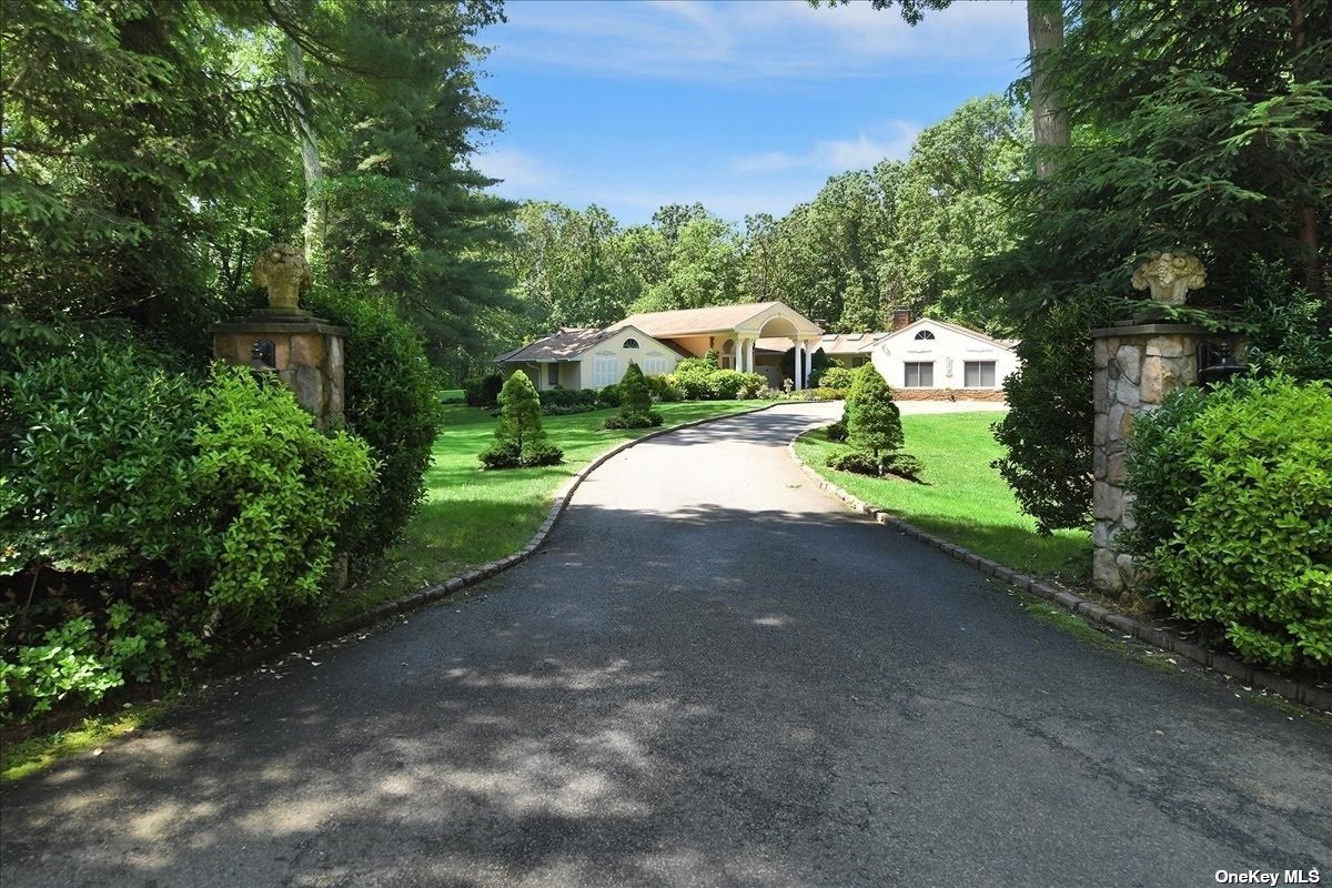 a view of a house with a small yard and large trees