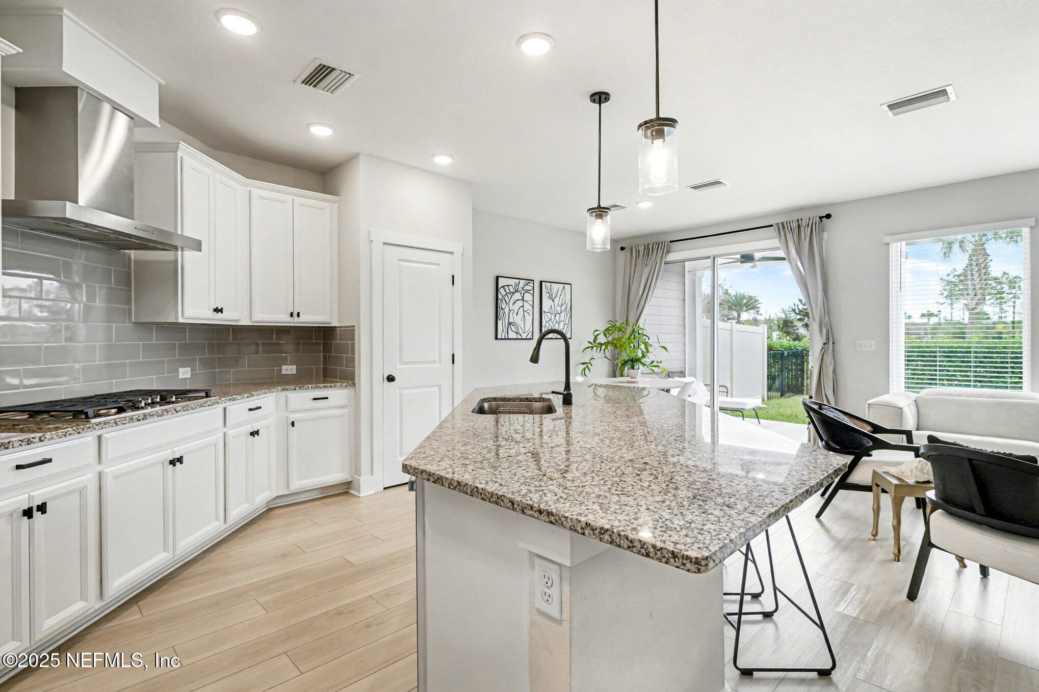 9858 Element Road Jacksonville, FL 32256 - Photo 12 of 19 a kitchen with kitchen island granite countertop a table chairs in it wooden floors and white cabinets