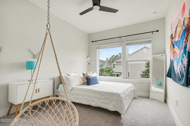 a bedroom with a bed next to a window with a chandelier