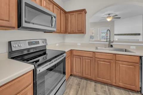 an empty room with wooden floor and a ceiling fan