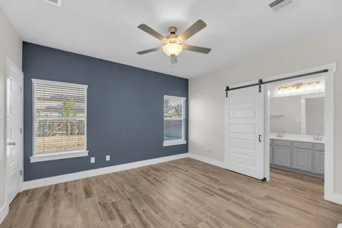 an empty room with wooden floor fan and windows