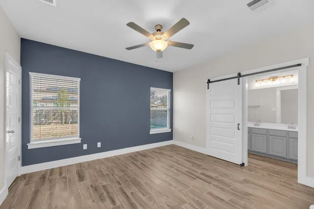 an empty room with wooden floor fan and windows