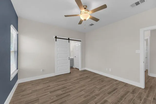 an empty room with wooden floor and windows