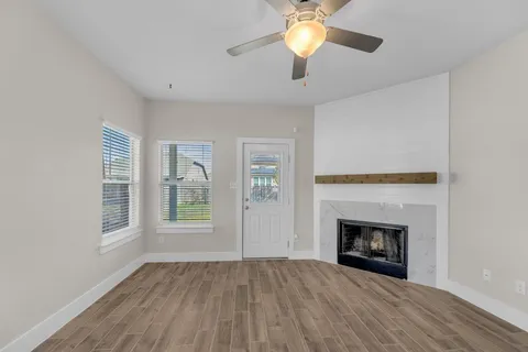an empty room with windows fireplace and fan