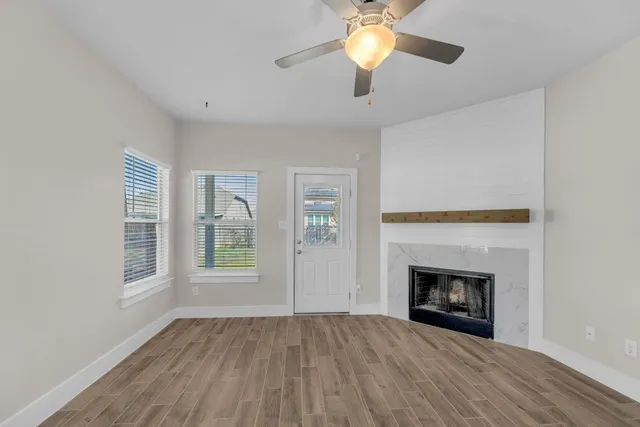 an empty room with windows fireplace and fan