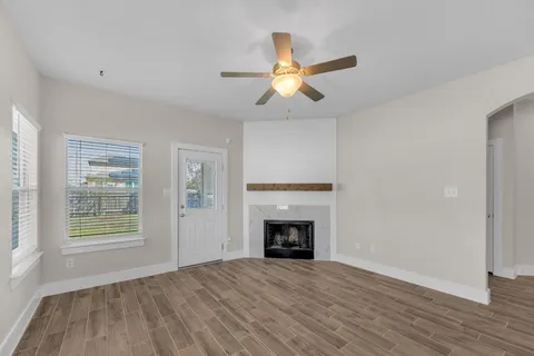 a view of an empty room with a fireplace and wooden floor