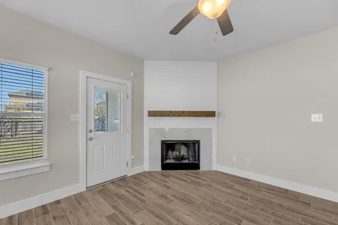 a view of a livingroom with wooden floor a ceiling fan and windows