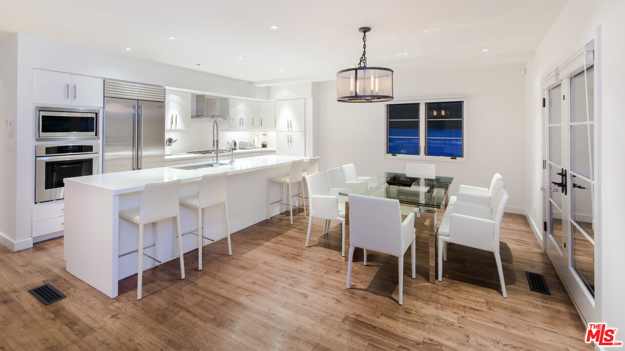 441 North Kings Road Los Angeles, CA 90048 - Photo 9 of 36 a kitchen with a dining table chairs and white cabinets