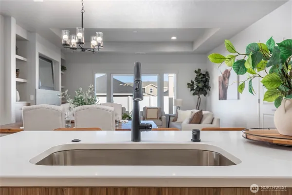 a kitchen with a sink a faucet a chandelier and living room view