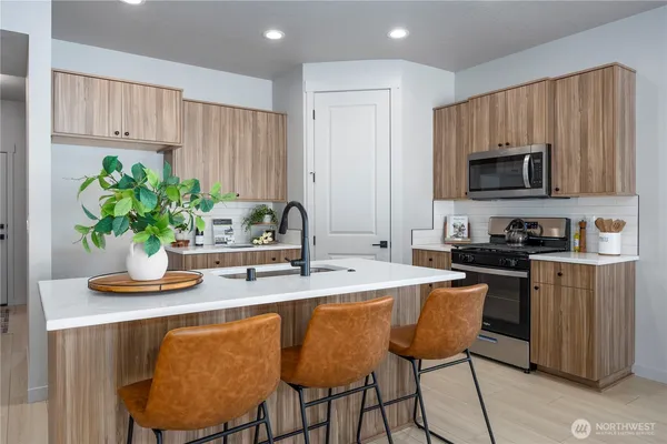 a kitchen with stainless steel appliances kitchen island granite countertop a sink a stove a dining table and chairs