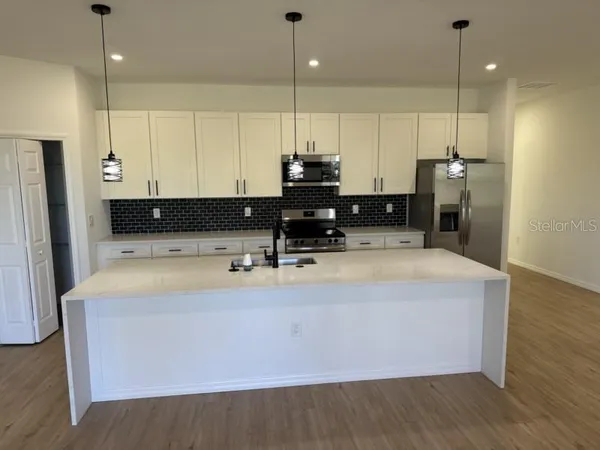 a view of kitchen with stainless steel appliances granite countertop a sink a refrigerator and a stove