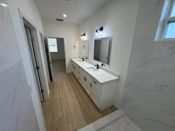 a view of bathroom with sink mirror and window