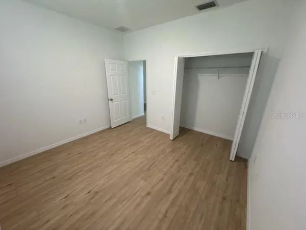 a view of an empty room with wooden floor and closet