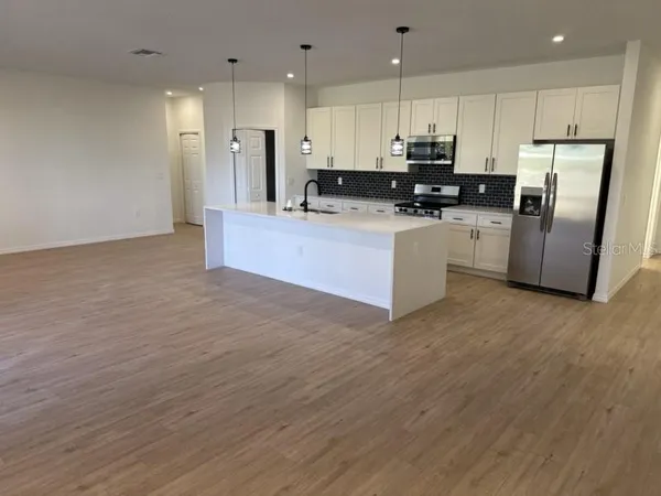 a kitchen with stainless steel appliances granite countertop a refrigerator sink and white cabinets