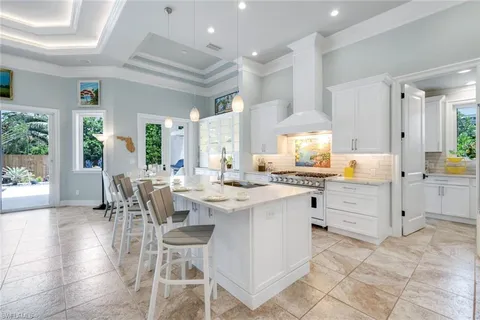 a kitchen with stainless steel appliances kitchen island granite countertop a table chairs and a refrigerator