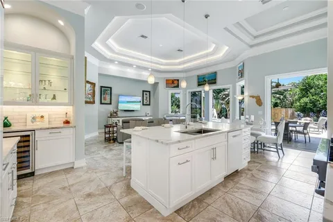 a large white kitchen with a large window and chairs