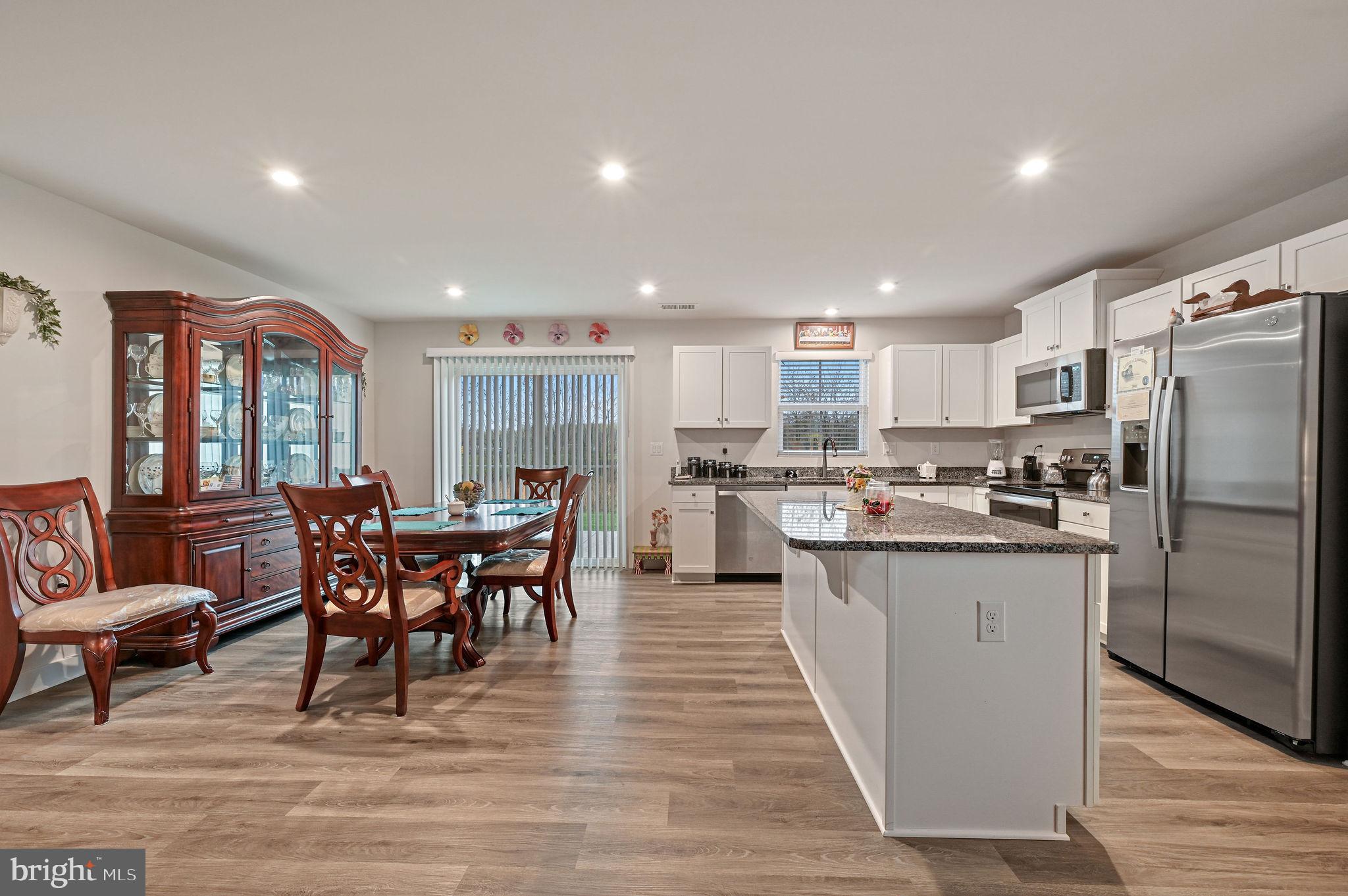 421 Laertes Drive Dover, DE 19901 - Photo 11 of 29 a kitchen with stainless steel appliances granite countertop a refrigerator a stove top oven a dining table and chairs with wooden floor