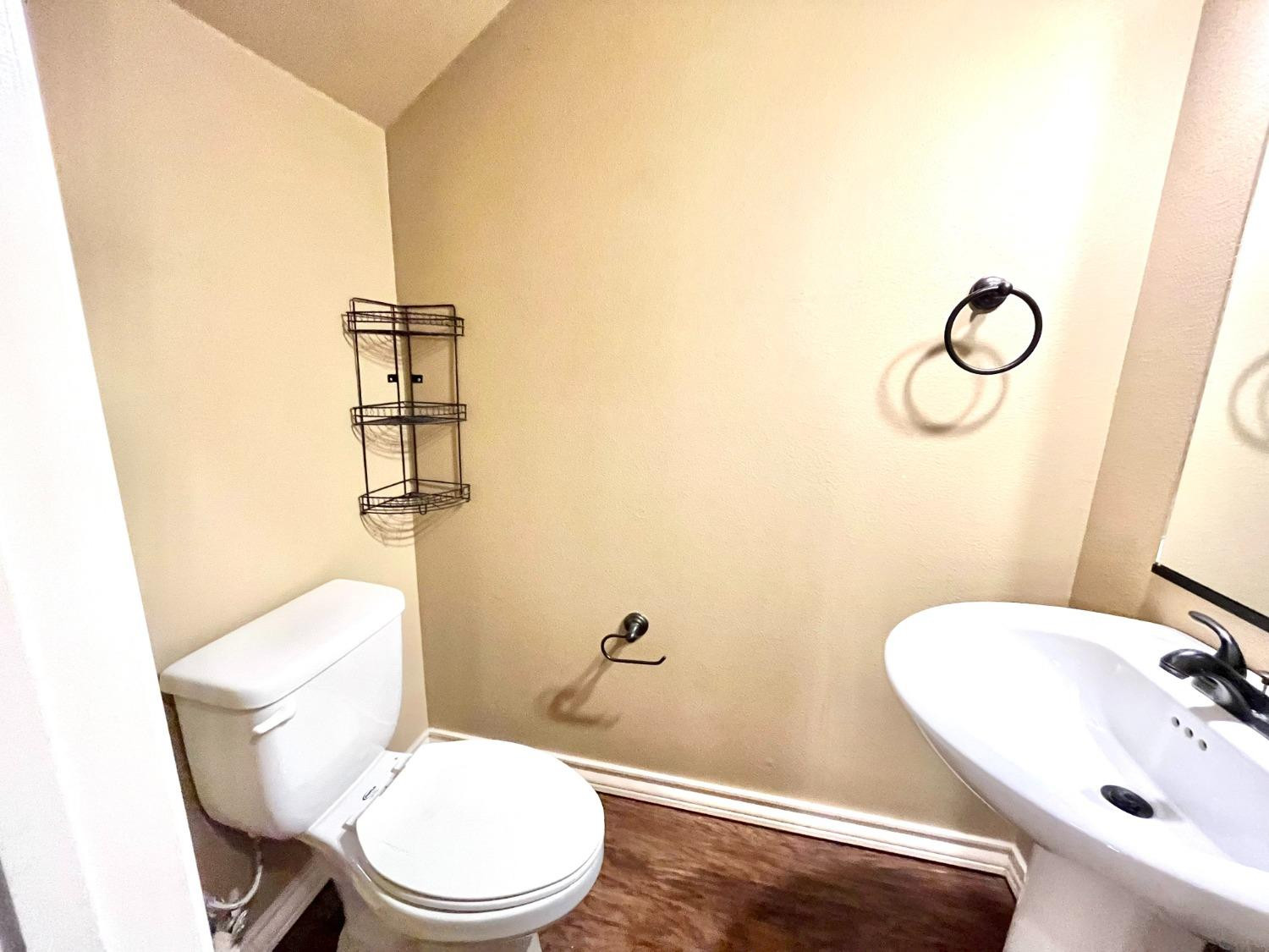4419 106th Street, Unit B Lubbock, TX 79424 - Photo 11 of 20 a white toilet sitting next to a bathroom sink and vanity