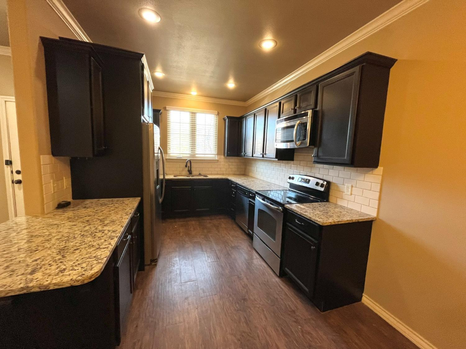 4419 106th Street, Unit B Lubbock, TX 79424 - Photo 4 of 20 a kitchen with stainless steel appliances granite countertop a stove refrigerator and sink