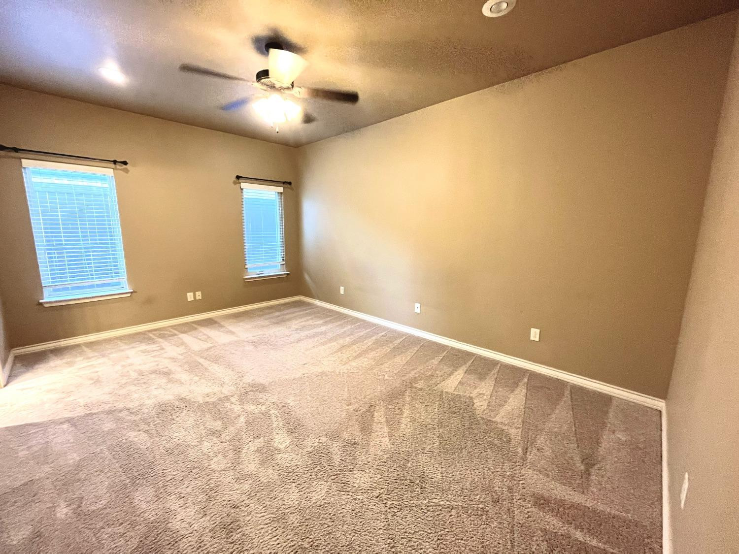 4419 106th Street, Unit B Lubbock, TX 79424 - Photo 6 of 20 an empty room with a chandelier fan and windows