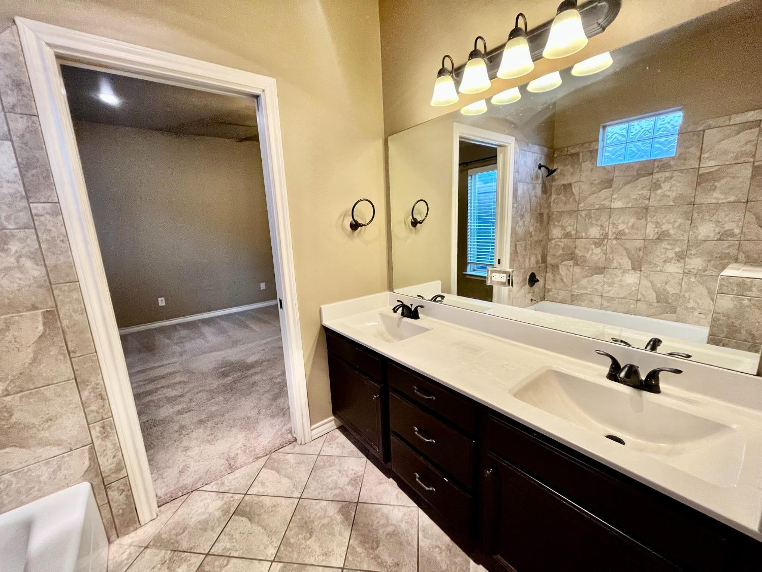 4419 106th Street, Unit B Lubbock, TX 79424 - Photo 9 of 20 a spacious bathroom with a double vanity sink a mirror and a shower