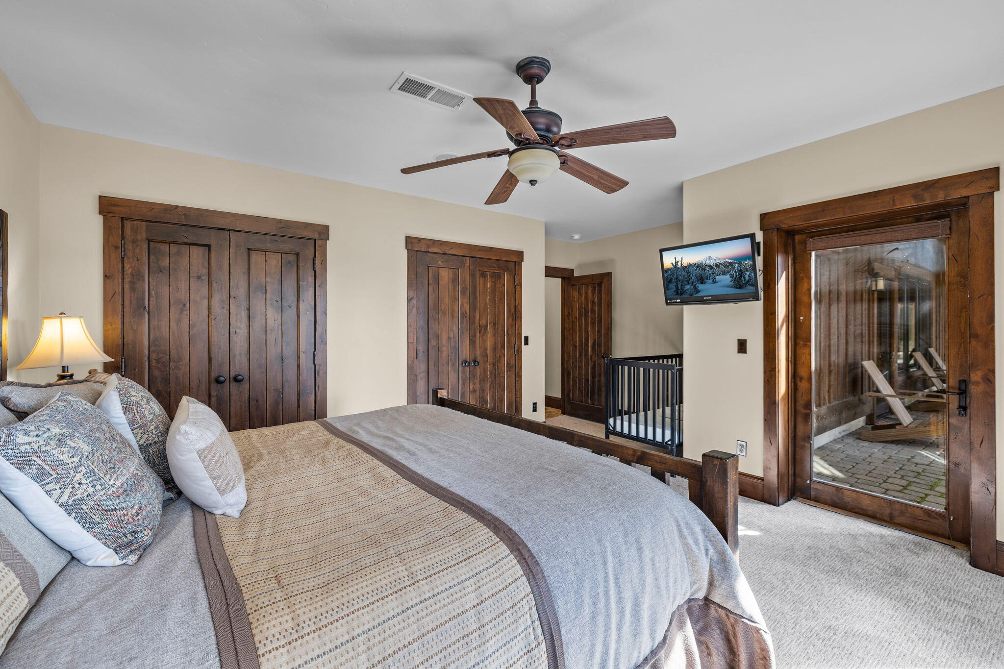 56373 Trailmere Circle Bend, OR 97707 - Photo 54 of 102 a bedroom with a bed and a large mirror with a flat tv screen