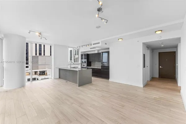 a view of a kitchen with kitchen island a sink wooden floor and living room