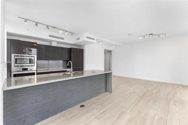 a view of a kitchen with kitchen island a counter top space a stove a sink and a refrigerator