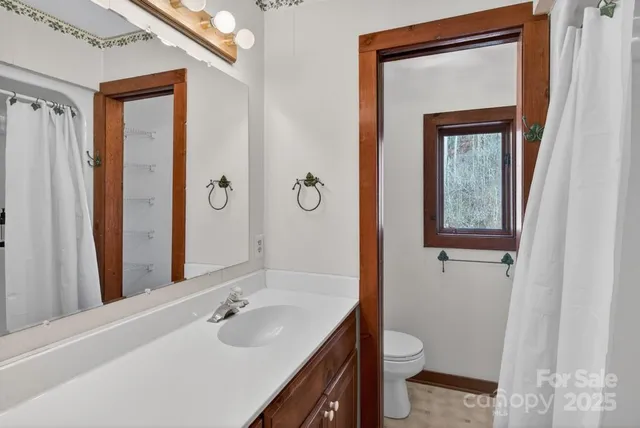 a bathroom with a toilet a sink a mirror and a window