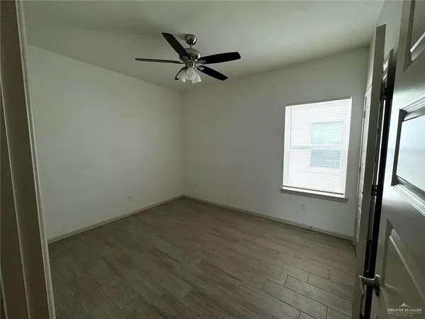 an empty room with wooden floor fan and windows