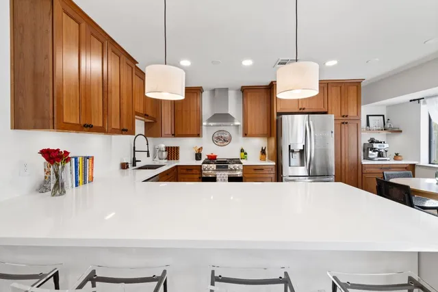 a large kitchen with stainless steel appliances a refrigerator a sink dishwasher a dining table and chairs with wooden floor