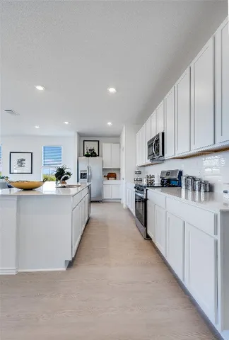 a large white kitchen with kitchen island a sink a center island stainless steel appliances and a cabinets