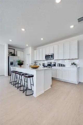 a kitchen with stainless steel appliances sink white cabinets and a refrigerator