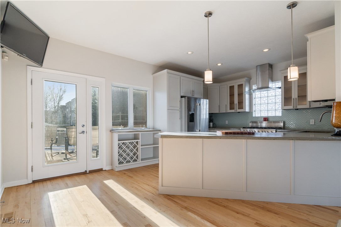 711 University Road Cleveland, OH 44113 - Photo 16 of 36 Kitchen featuring stainless steel fridge with ice dispenser, sink, hanging light fixtures, kitchen peninsula, and wall chimney range hood