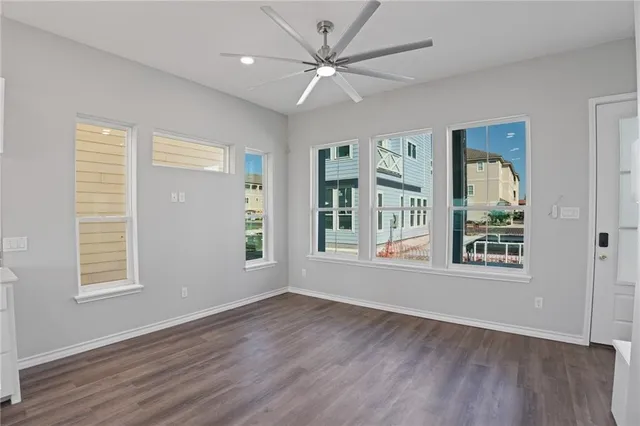 a view of an empty room with a window and wooden floor