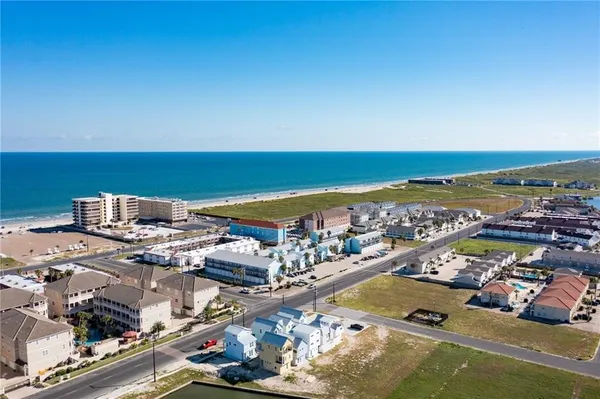 an aerial view of ocean and residential houses with outdoor space