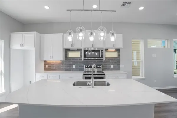 a kitchen with kitchen island a counter top space cabinets and stainless steel appliances