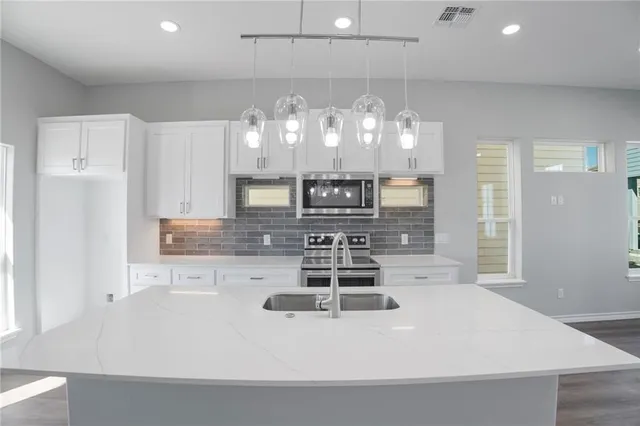 a kitchen with kitchen island a counter top space cabinets and stainless steel appliances
