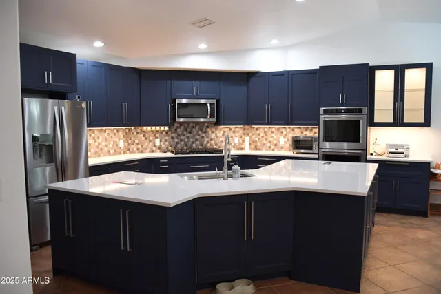 a kitchen with a chandelier stainless steel appliances a sink and a refrigerator